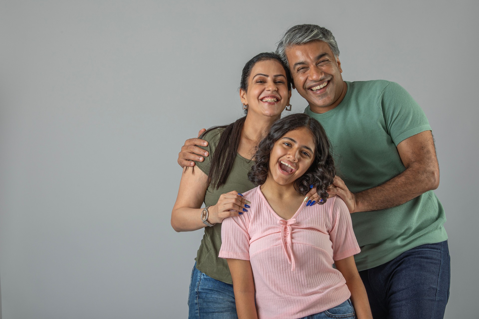 Loving parents embracing daughter over white background